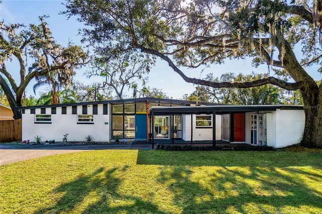 mid-century modern home with a front yard and fence