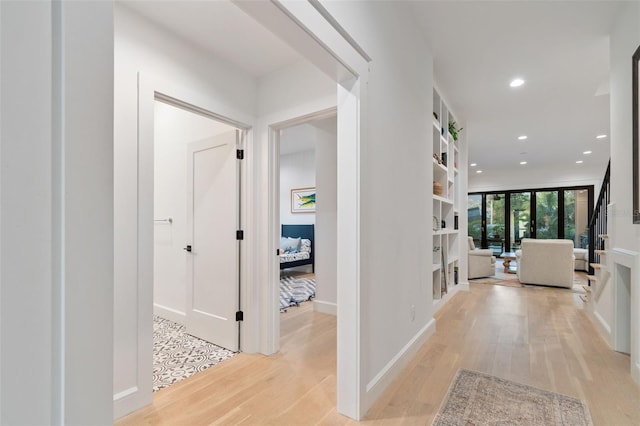 corridor with expansive windows and light hardwood / wood-style floors