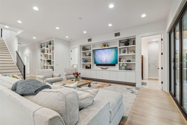 living room with built in features and light hardwood / wood-style flooring