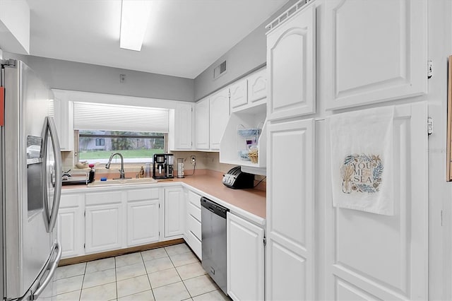 kitchen with white cabinets, sink, stainless steel appliances, and light tile patterned flooring