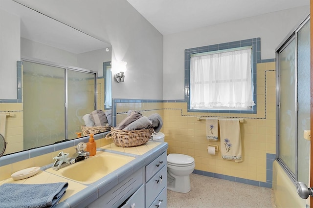 full bathroom with tile walls, toilet, vanity, and combined bath / shower with glass door