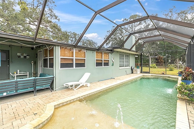 view of pool with glass enclosure, outdoor lounge area, pool water feature, and a patio area