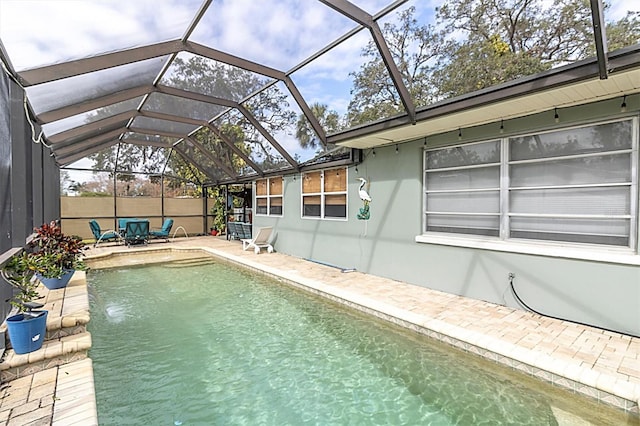 view of swimming pool with pool water feature, glass enclosure, and a patio