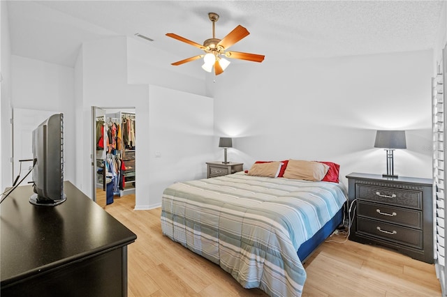 bedroom featuring a spacious closet, a closet, a textured ceiling, and light wood-type flooring