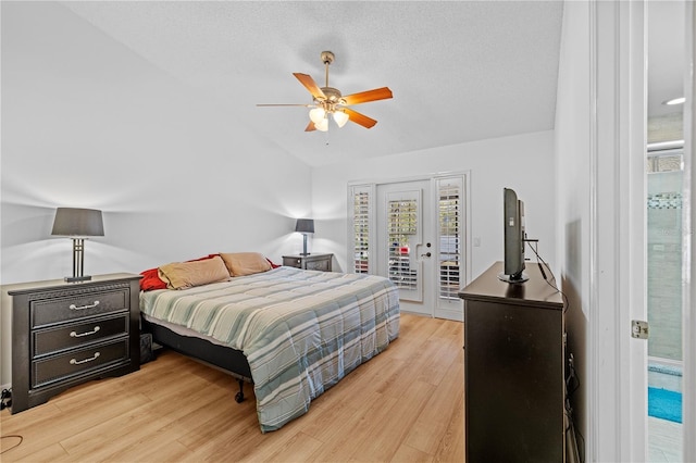 bedroom with vaulted ceiling, hardwood / wood-style flooring, access to outside, ceiling fan, and a textured ceiling