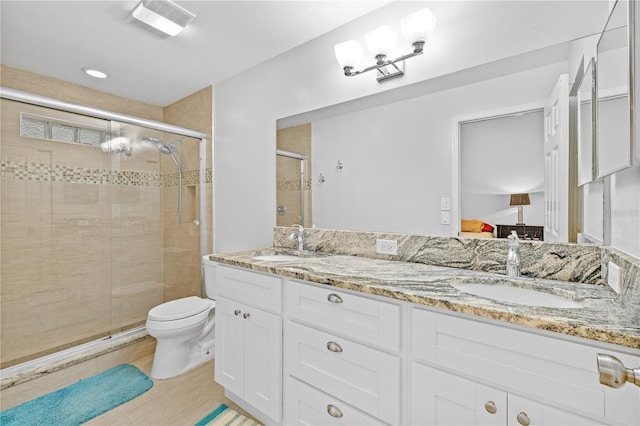 bathroom featuring vanity, a shower with shower door, and toilet