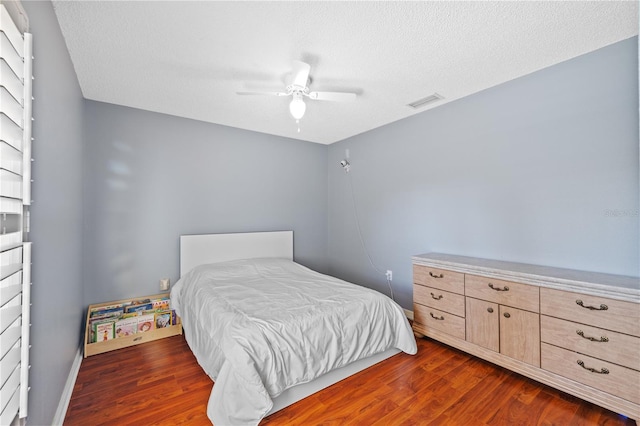 bedroom with ceiling fan, dark hardwood / wood-style flooring, and a textured ceiling