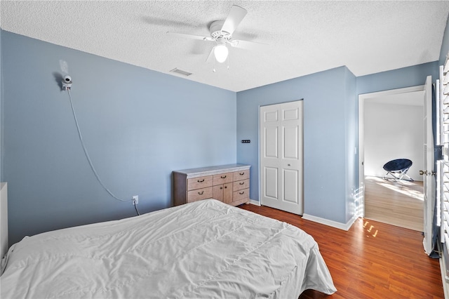 bedroom featuring ceiling fan, wood-type flooring, and a textured ceiling