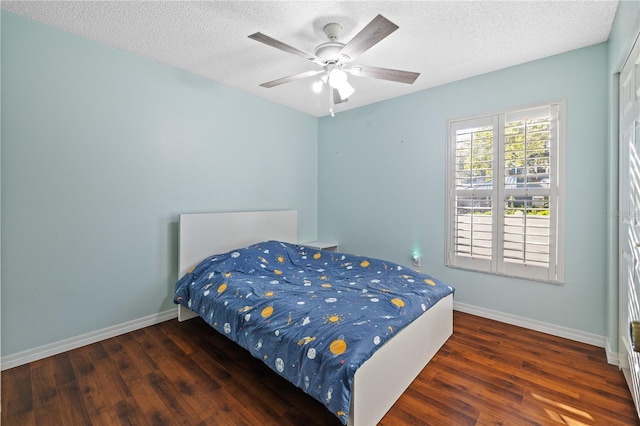 bedroom featuring ceiling fan, dark hardwood / wood-style floors, and a textured ceiling