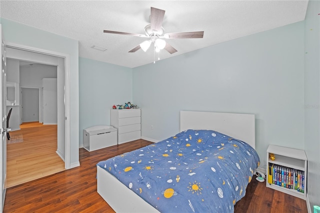 bedroom with dark hardwood / wood-style flooring, ceiling fan, and a textured ceiling