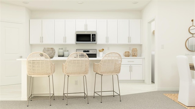 kitchen with range, white cabinetry, and a kitchen breakfast bar