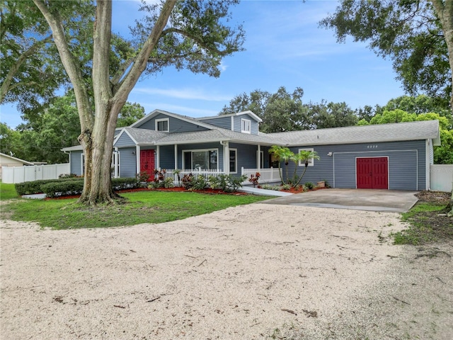 view of front of house with covered porch, a front yard, and a garage