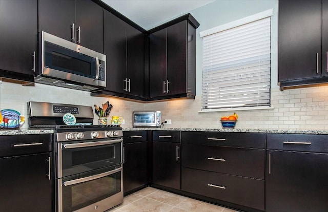 kitchen featuring decorative backsplash, light stone counters, light tile patterned floors, and stainless steel appliances