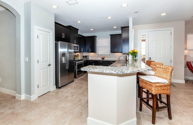 kitchen with a kitchen breakfast bar, sink, light stone countertops, appliances with stainless steel finishes, and kitchen peninsula