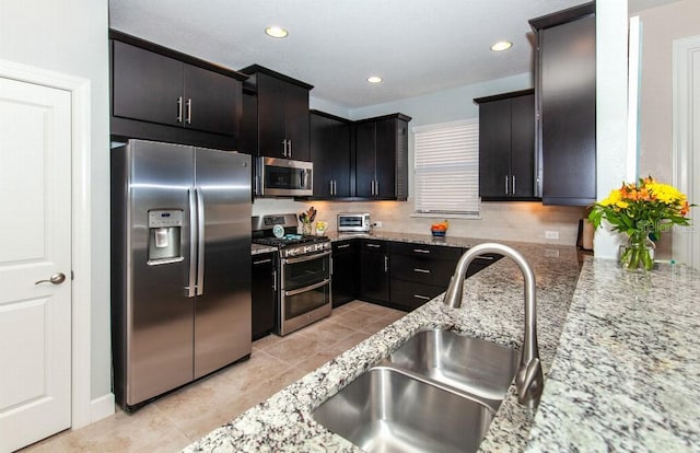 kitchen featuring light stone countertops, sink, light tile patterned floors, and stainless steel appliances