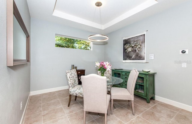 tiled dining room featuring a tray ceiling