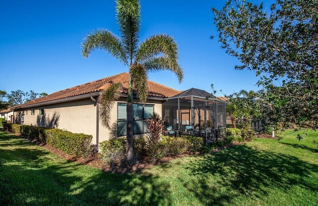 rear view of property featuring a lawn and a lanai