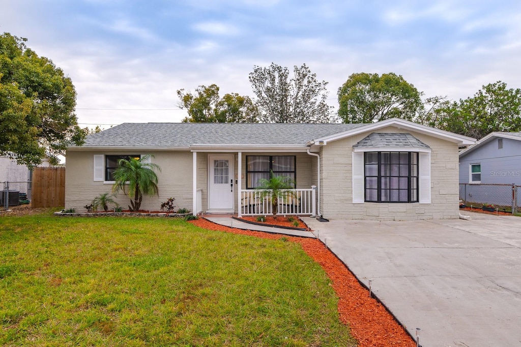 ranch-style home with a porch, central air condition unit, and a front lawn