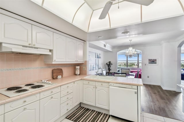 kitchen with pendant lighting, white appliances, sink, backsplash, and kitchen peninsula