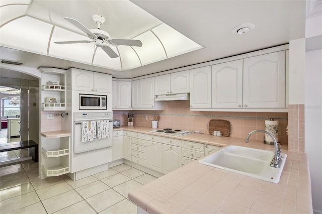 kitchen with white appliances, white cabinetry, sink, ceiling fan, and light tile patterned floors