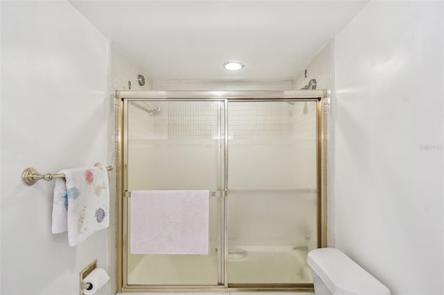 bathroom with a shower with shower door and toilet