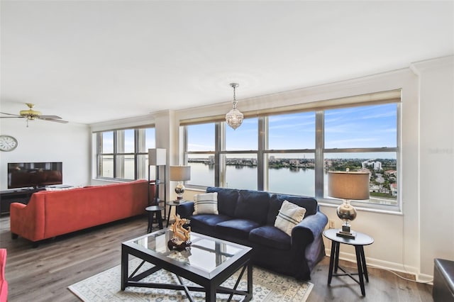 living room with ceiling fan, hardwood / wood-style flooring, ornamental molding, and a water view