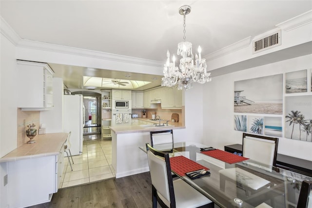 dining area with ceiling fan with notable chandelier, dark hardwood / wood-style flooring, and crown molding