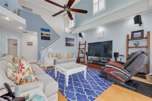 living room with hardwood / wood-style floors, ceiling fan, crown molding, and a high ceiling