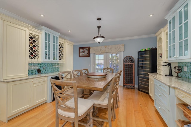 dining space with beverage cooler, light wood-type flooring, and ornamental molding