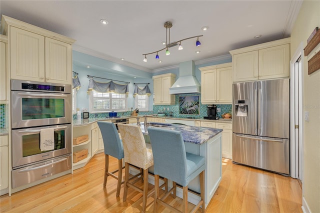 kitchen featuring a center island, stainless steel appliances, premium range hood, cream cabinets, and a breakfast bar area