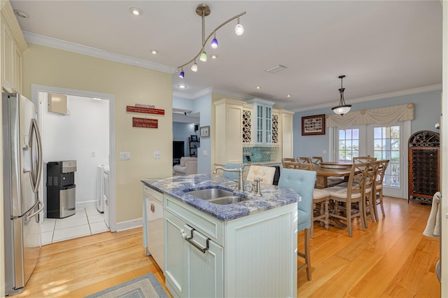 kitchen featuring dark stone counters, sink, stainless steel refrigerator with ice dispenser, independent washer and dryer, and an island with sink