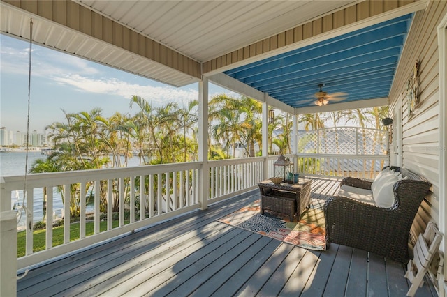 wooden deck featuring ceiling fan, a water view, and an outdoor living space