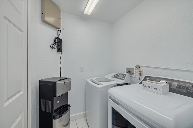 laundry area with washer and clothes dryer and light tile patterned floors