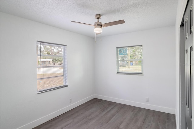 empty room with a textured ceiling, ceiling fan, and dark hardwood / wood-style flooring