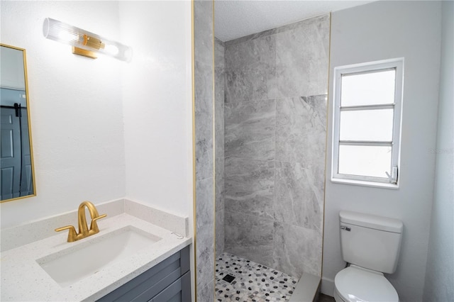 bathroom featuring tiled shower, toilet, and vanity