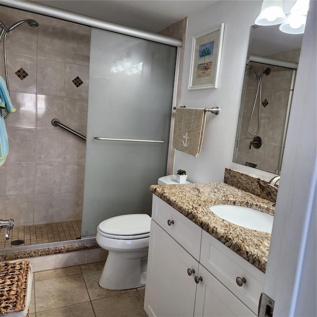 bathroom featuring tile patterned floors, vanity, toilet, and a shower with door