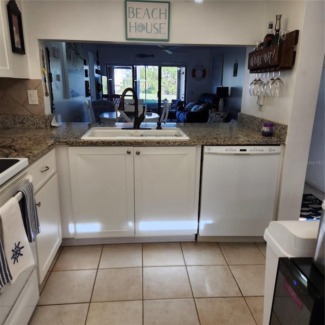 kitchen with decorative backsplash, white appliances, sink, light tile patterned floors, and white cabinets