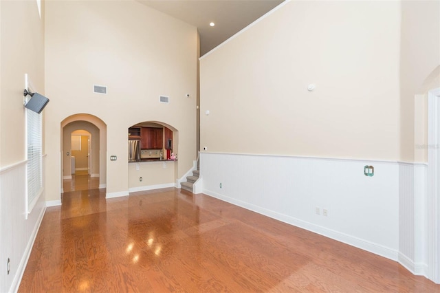 unfurnished living room with hardwood / wood-style floors and a towering ceiling