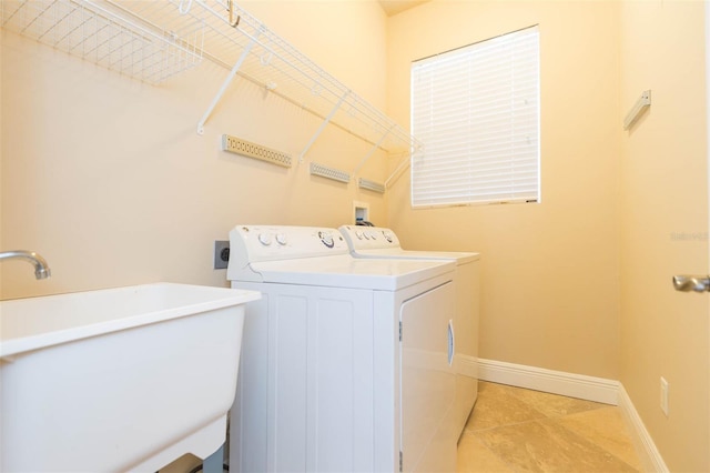 laundry area featuring light tile patterned flooring, washing machine and dryer, and sink