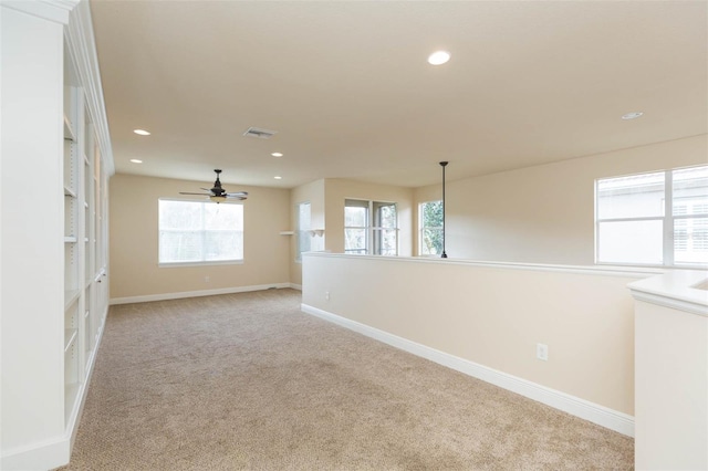 empty room featuring ceiling fan and light colored carpet