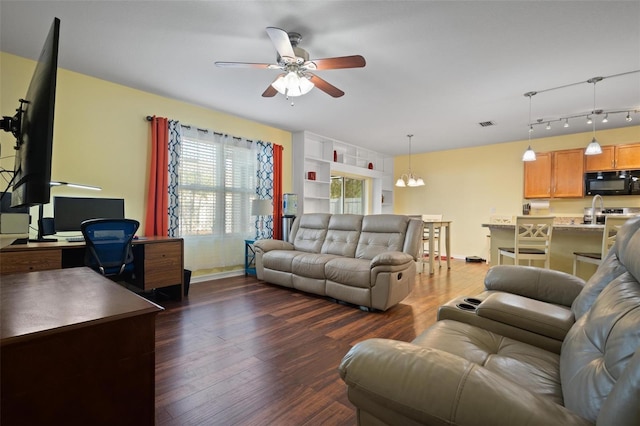 living room with ceiling fan with notable chandelier and dark wood-type flooring