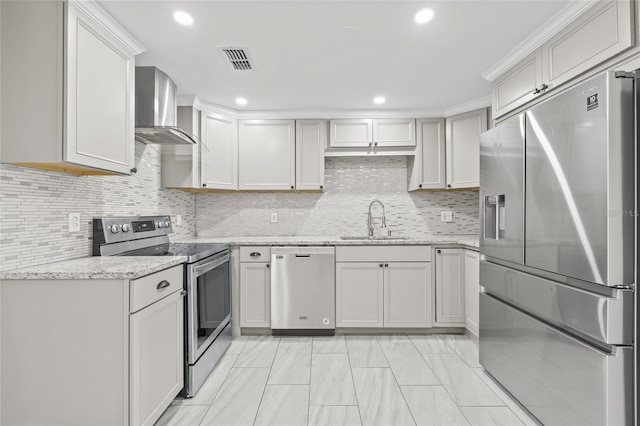 kitchen with sink, wall chimney exhaust hood, light stone countertops, tasteful backsplash, and stainless steel appliances