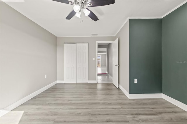 unfurnished bedroom featuring light wood-type flooring, a closet, ceiling fan, and ornamental molding