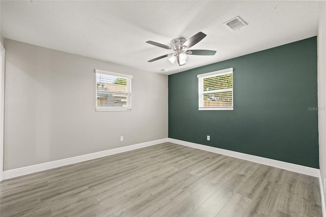 spare room with ceiling fan, light wood-type flooring, and a wealth of natural light