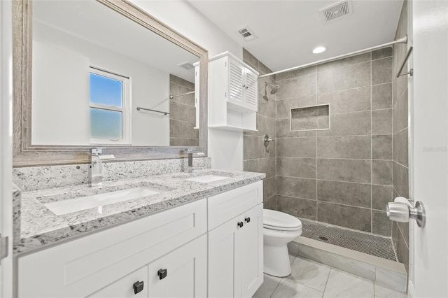 bathroom with vanity, toilet, and tiled shower