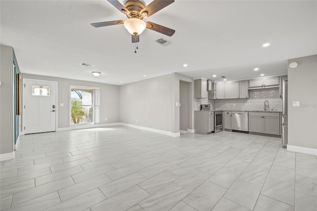 unfurnished living room featuring ceiling fan and sink