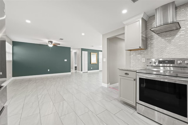 kitchen with wall chimney range hood, tasteful backsplash, light stone counters, stainless steel range with electric stovetop, and white cabinets