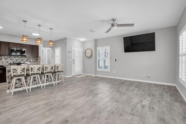 unfurnished living room with light wood-type flooring and ceiling fan