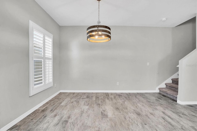 unfurnished room featuring a chandelier and light wood-type flooring