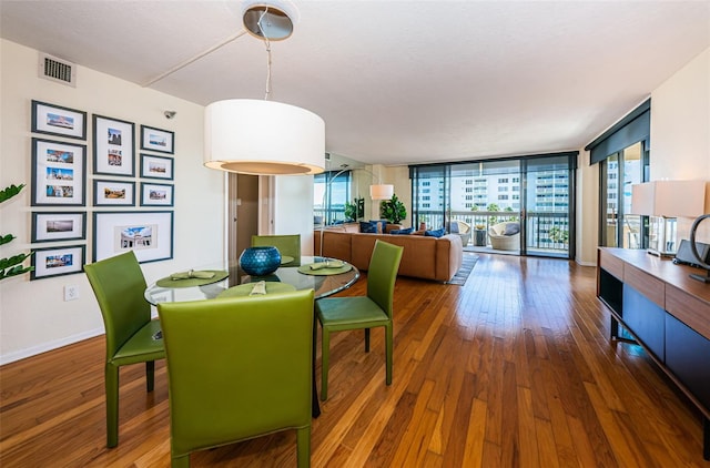 dining room with a wall of windows and dark hardwood / wood-style floors